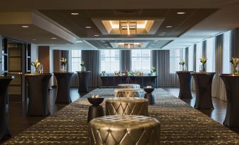 a room with a high ceiling and large windows , featuring gold stools and black tables at Renaissance Allentown Hotel