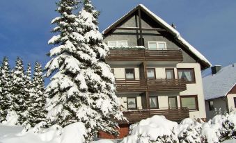 a snow - covered house with a staircase leading up to the second floor , surrounded by trees and covered in snow at Raeck
