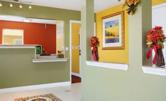 a modern office space with green and yellow walls , a white ceiling , and a wooden reception desk at La Quinta Inn & Suites by Wyndham Houston Channelview