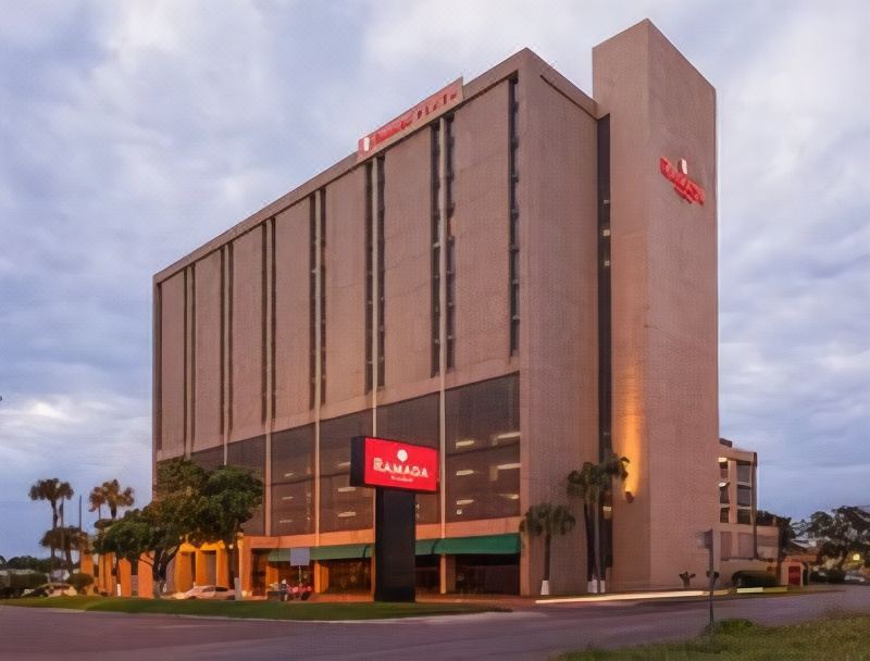 a large hotel with a red sign on the front and a white building in the background at Hotel Ava Laredo