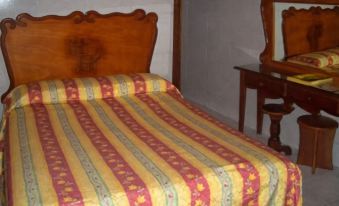 a bed with a striped blanket and a wooden headboard is in a room next to a wooden table at Hotel Posada del Hidalgo