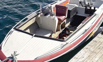 a small boat with a red and white hull is docked at a wooden pier at Helgeland