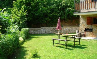 a garden with a table and an umbrella , surrounded by green grass and a stone wall at Baracka