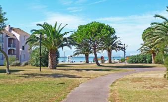 a park with a paved path surrounded by palm trees and a body of water at Antigua
