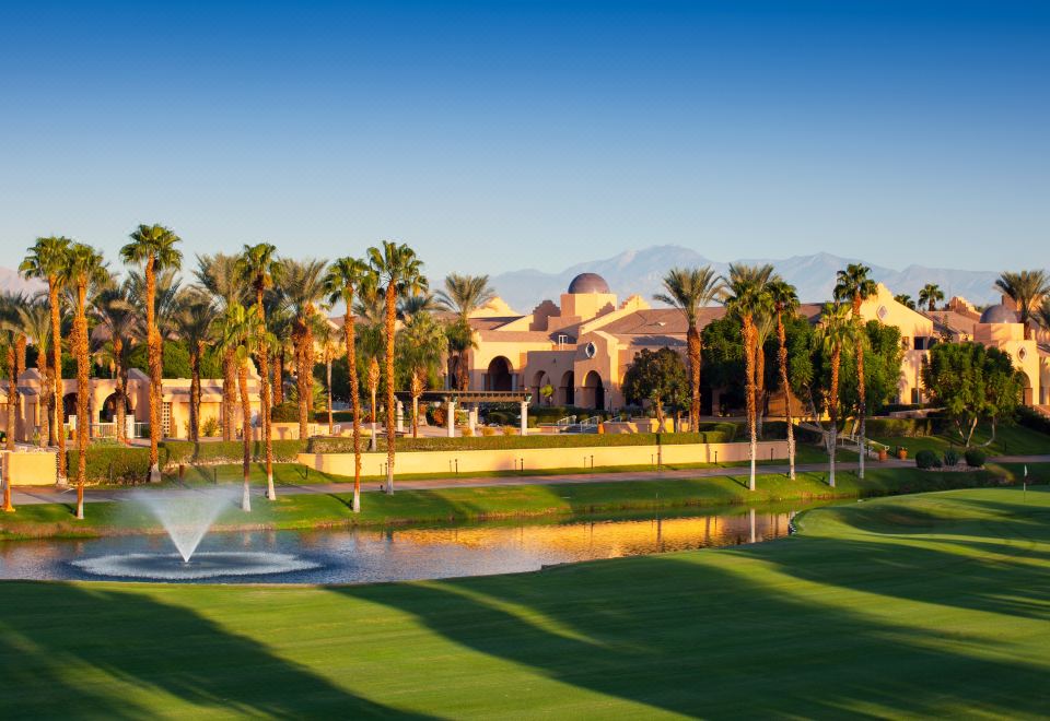 a large building with palm trees and a fountain in front of it , surrounded by grass and trees at The Westin Rancho Mirage Golf Resort & Spa