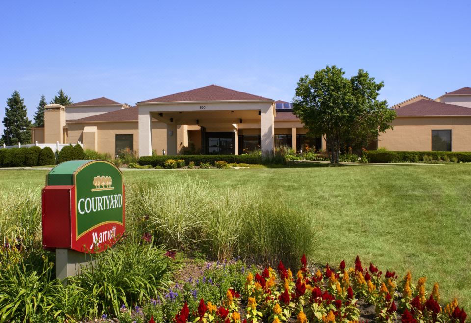 a courtyard by marriott hotel surrounded by a lush green lawn , with a sign indicating the entrance at Courtyard Chicago Deerfield