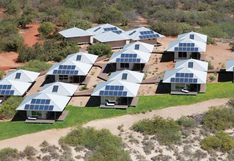 aerial view of a group of solar panels on a building in the desert , surrounded by grass and trees at Eco Beach Wilderness Retreat