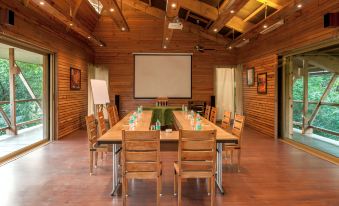 a wooden conference room with a large table , chairs , and a projector screen , set up for a meeting or presentation at The Machan