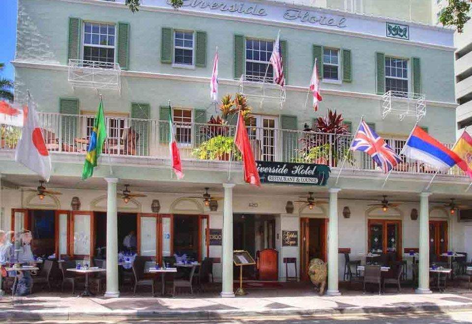 a multi - story building with a balcony and several flags , possibly for international organizations or charitable organizations at Riverside Hotel