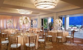 a well - decorated banquet hall with multiple tables set for a formal event , featuring multiple chandeliers hanging from the ceiling at 1 Hotel Hanalei Bay