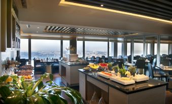 The restaurant features large windows and tables in the center, providing a view of the outside scenery from the interior at The Marmara Taksim