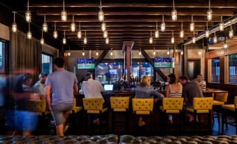 a group of people are sitting at a bar with yellow chairs and lights hanging from the ceiling at Hotel Nyack, A Joie de Vivre Hotel by Hyatt