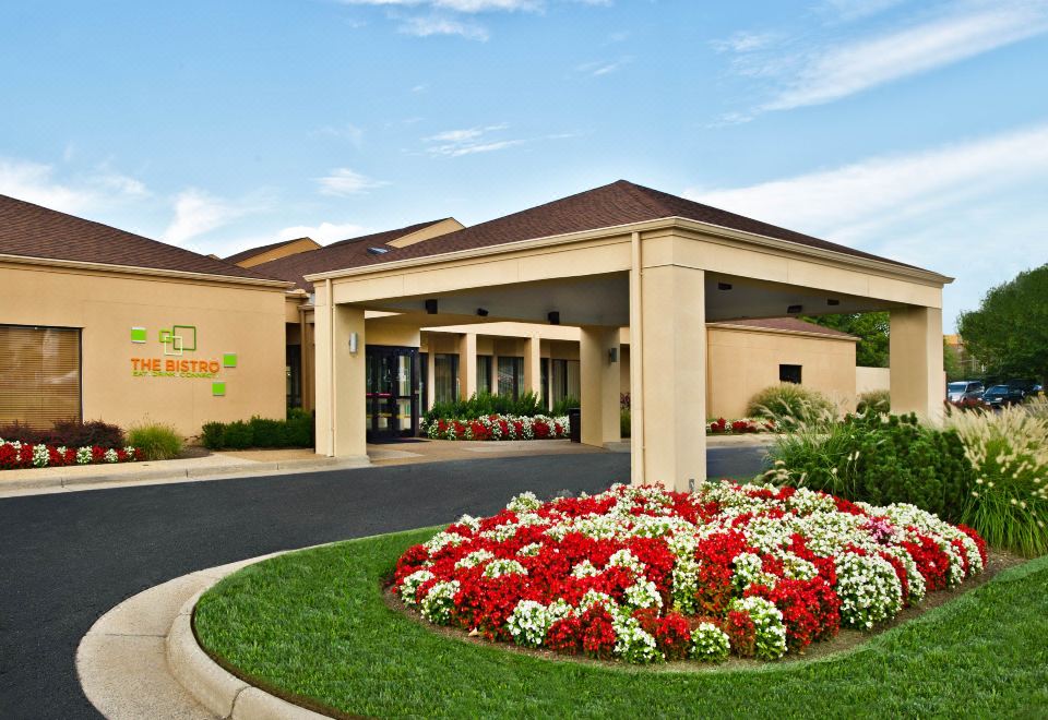 a hotel entrance with a large flower bed in front of it , creating a welcoming atmosphere at Courtyard by Marriott Fairfax Fair Oaks