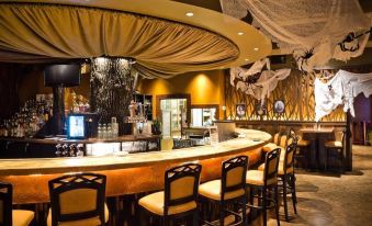 a well - lit bar with a long wooden counter , several chairs , and a variety of bottles at Heritage Hotel Lancaster