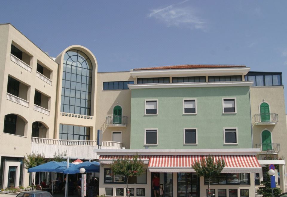 a building with a large arched window and two red and white striped awnings is shown at Hotel Bellevue Trogir