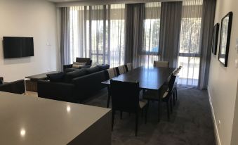 a modern living room with a large dining table and chairs , a couch , and a television at Knightsbridge Canberra