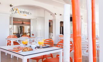 an outdoor dining area with orange chairs and tables , orange food on the table , and white walls at Typic Oasis Sa Tanca