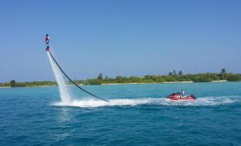 a person is parasailing over the ocean , surrounded by water and a boat in the background at Paradise Lagoon