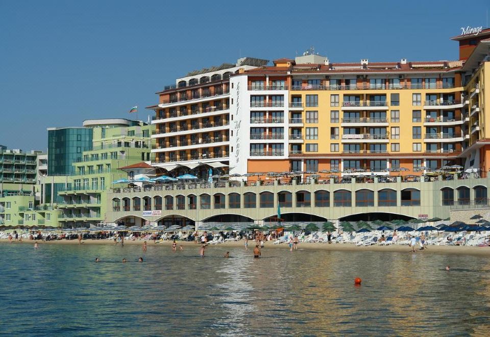 a large building with a bridge over a body of water , surrounded by people and boats at Mirage Hotel