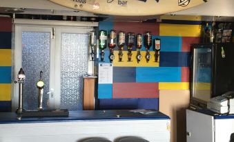 a surfboard hanging on the wall of a colorful bar with stools and a bar area at Breakers