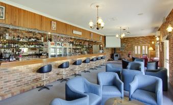 a bar area with several chairs and tables , as well as a television mounted on the wall at Parkes International