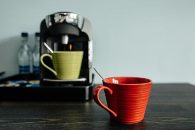 a red coffee cup sits on a dining table next to a coffee maker and a pitcher at Village Hotel Liverpool