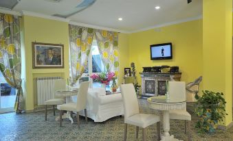 a well - decorated living room with yellow walls , white furniture , and a television on the wall at Hotel Miramare