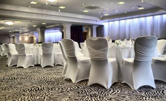 a conference room set up for a meeting , with chairs arranged in rows and tables covered in white tablecloths at Glynhill Hotel & Spa Near Glasgow Airport