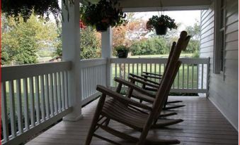 a wooden porch with two rocking chairs , one on each side of the porch , surrounded by a grassy field at Seventy-Four Ranch