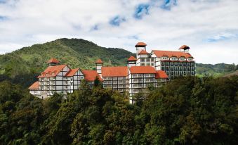a large hotel surrounded by trees and mountains , with a cloudy sky in the background at Heritage Hotel Cameron Highlands