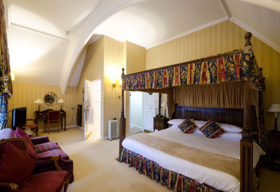 a luxurious hotel room with a four - poster bed in the center , surrounded by various pieces of furniture at The Snooty Fox
