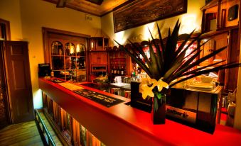 a bar with a red countertop , surrounded by shelves filled with wine bottles and glasses at Poet's Recall Motel