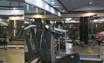 a well - equipped gym with various exercise equipment , including treadmills and weight machines , reflected in the mirror at Angaga Island Resort and Spa