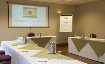 a conference room set up for a meeting , with multiple chairs arranged in rows and a projector on the wall at Brandon House Hotel