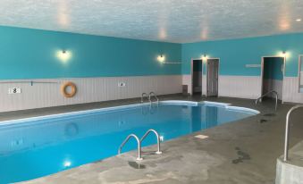 an empty indoor swimming pool with blue and white walls , surrounded by a concrete floor at Fairway Inn