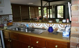 a modern kitchen with wooden cabinets , marble countertops , and a blue vase on the window sill at Riverhouse at Howqua Dale