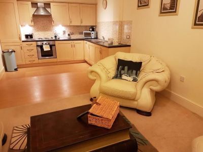 a cozy living room with a yellow couch and a wooden coffee table , as well as a kitchen area at Knights