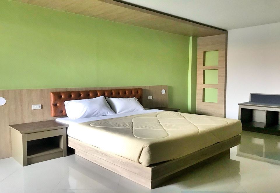 a large bed with a wooden headboard and footboard is situated in a room with green walls at Lopburi Residence Hotel