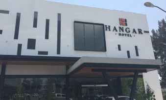 "a white building with a black sign that says "" hangar hotel "" and cars parked in front" at Hangar Inn Guadalajara Aeropuerto