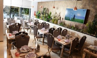 a restaurant with wooden tables and chairs , a large screen on the wall , and potted plants at Marigold Hotel