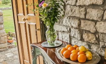 a wooden table with a plate of oranges and a vase of flowers next to a stone door at El Lucero