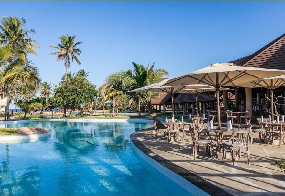 a resort with a large pool surrounded by lounge chairs and umbrellas , providing a relaxing atmosphere at Amani Tiwi Beach Resort