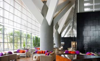 a large , modern living room with multiple couches and chairs arranged around a dining table at Hotel Maya Kuala Lumpur City Centre