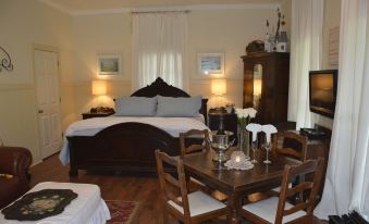 a spacious bedroom with a large bed , wooden furniture , and a dining table set for four at Southern Rose Ranch