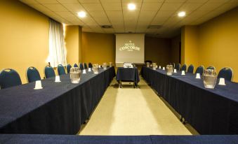 a large conference room with multiple rows of chairs arranged in a semicircle , and a projector on the wall at Hotel Concorde