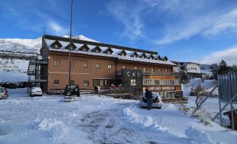 "a snow - covered building with a sign that says "" cat hotel "" and two people sitting on a motorcycle" at Rifugio Sapienza