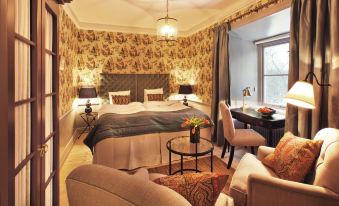 a luxurious hotel room with a king - sized bed , two chairs , a desk , and a window at Rosersbergs Slottshotell