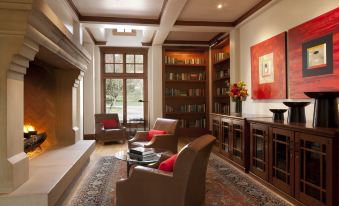 a cozy living room with wooden furniture , including a couch , chairs , and a bookshelf filled with books at CordeValle