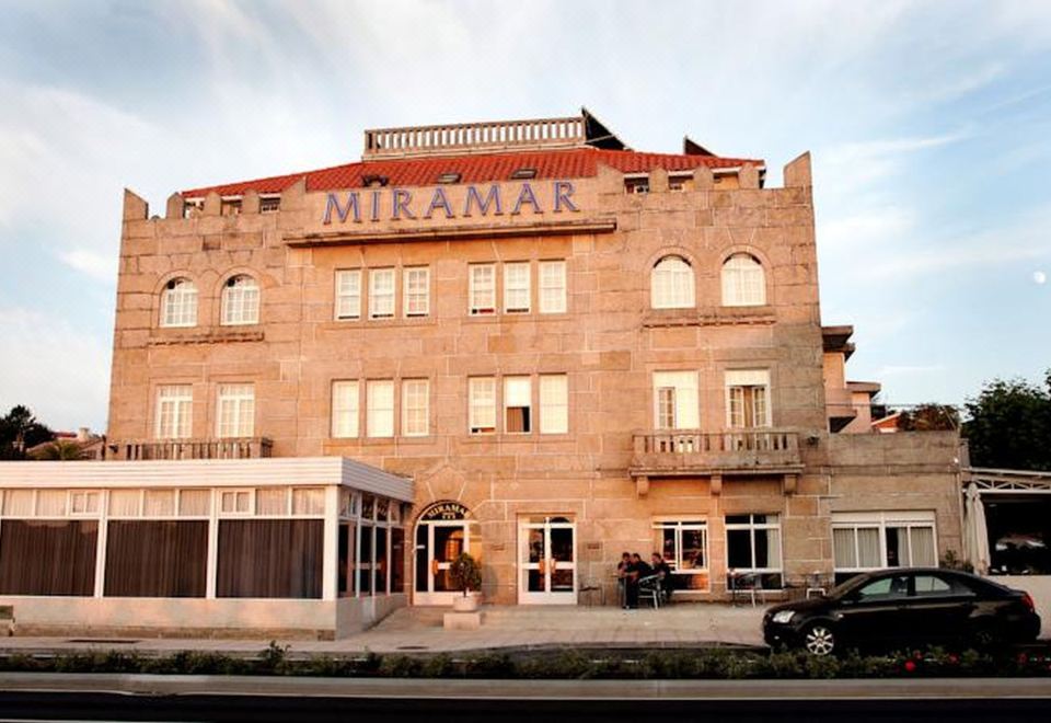 "a large stone building with the name "" miramar "" on it , situated in a city street" at Hotel Miramar Playa America Nigran