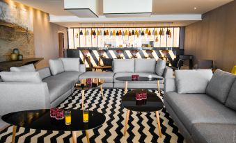 a modern living room with gray couches and chairs , a black and white chevron patterned rug , and multiple bottles on shelves at Simon Hotel